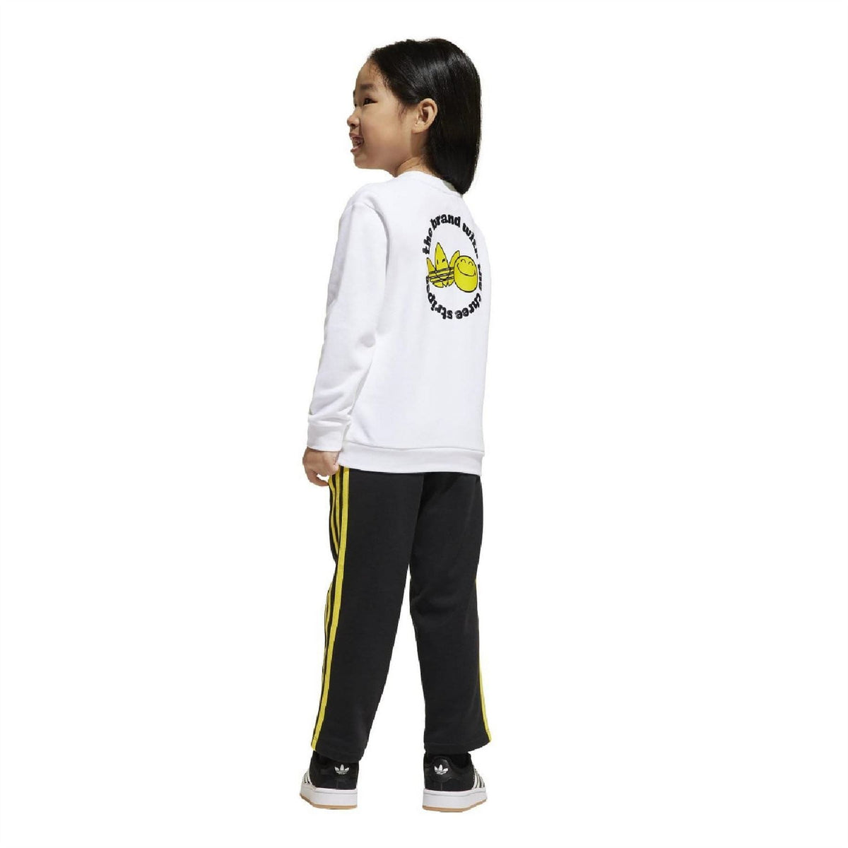 Kids white crewneck sweatshirt with back graphic and black track pants with yellow stripes