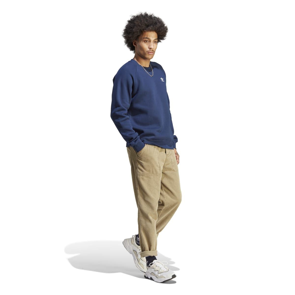 Navy crewneck sweatshirt with adidas logo, model side view with tan pants