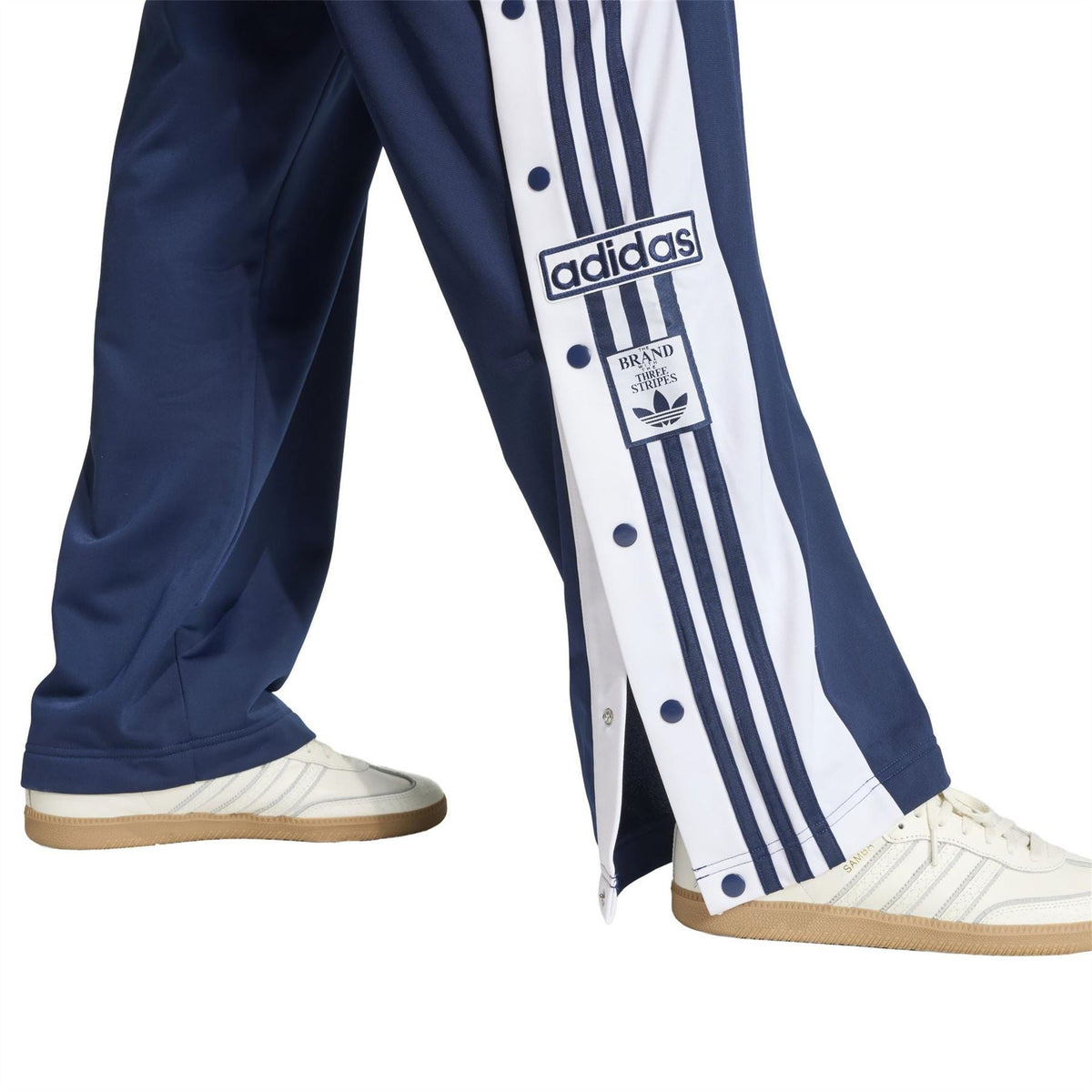 Indigo track joggers with side stripe, adidas badge, and open hem at ankle