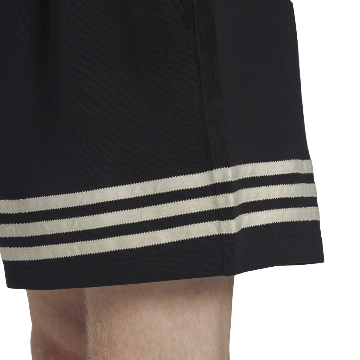 Close-up of black shorts hem with three cream and dark stripes