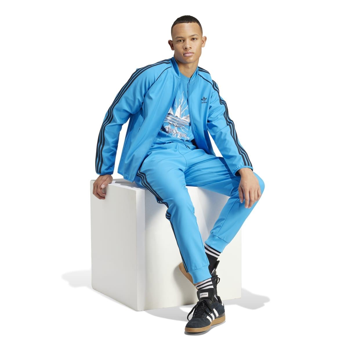 Blue adidas track jacket with black triple stripe detailing on sleeves and shoulders