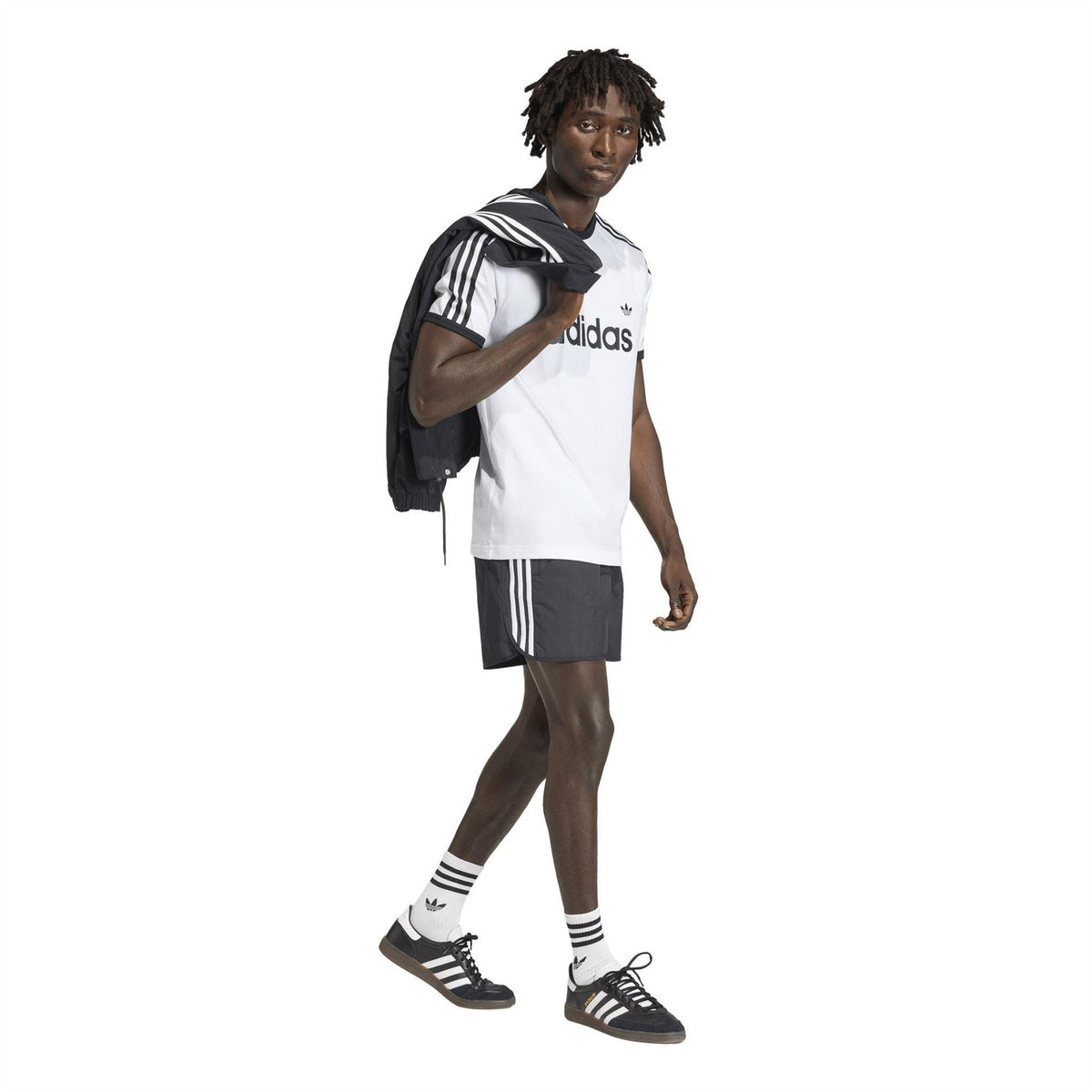 adidas Originals black track shorts with white stripes, worn with sneakers and crew socks