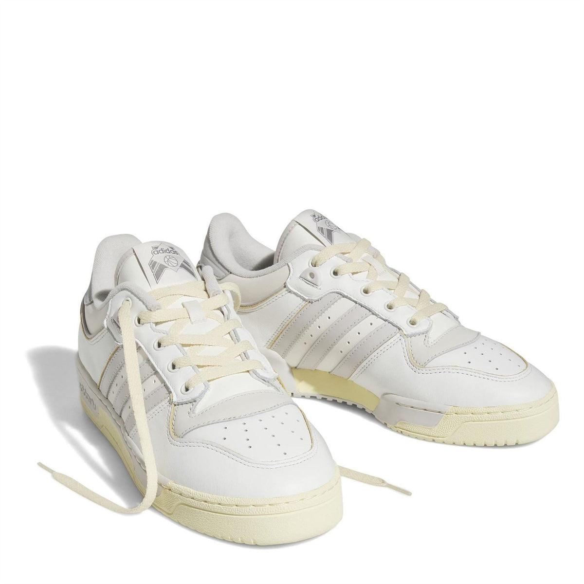 Pair of white lace-up low-top adidas trainers with three stripes and gum-colored sole.