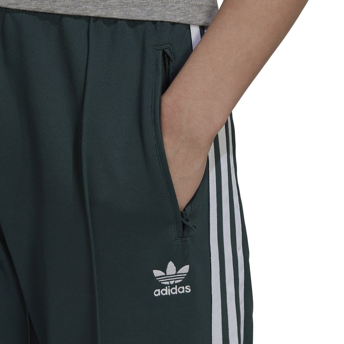 Dark green track pants close-up with adidas logo at left thigh