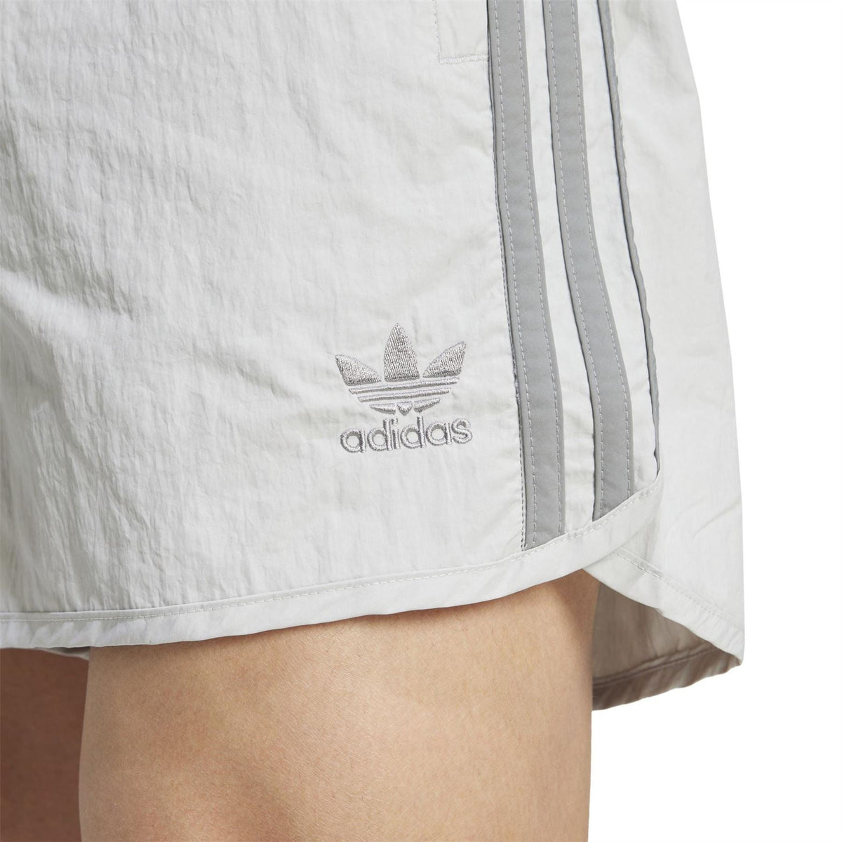 Light grey shorts close-up with adidas trefoil logo and side stripe panel