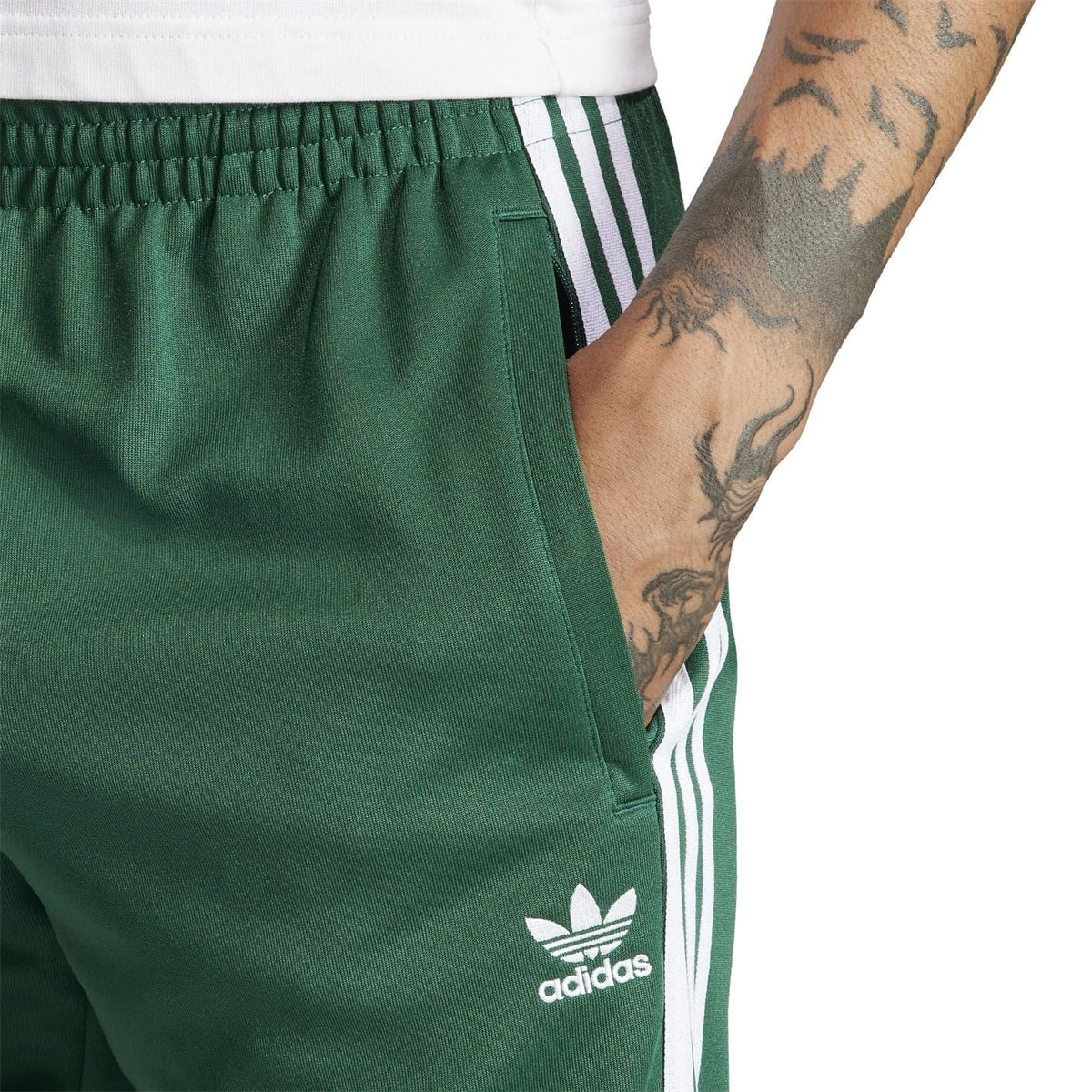 Green slim track pants detail: adidas logo on thigh and three stripe panel