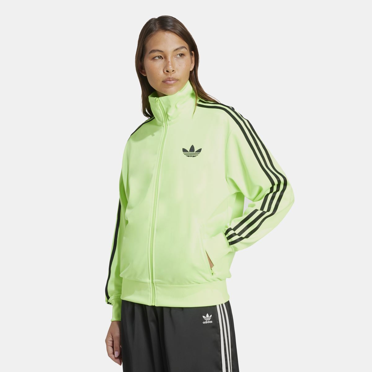 Lime green zip track jacket with stand collar, trefoil logo, and black sleeve stripes