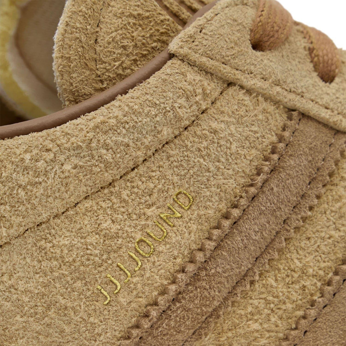 JJJound embossed on brown suede side panel of a lace-up trainer