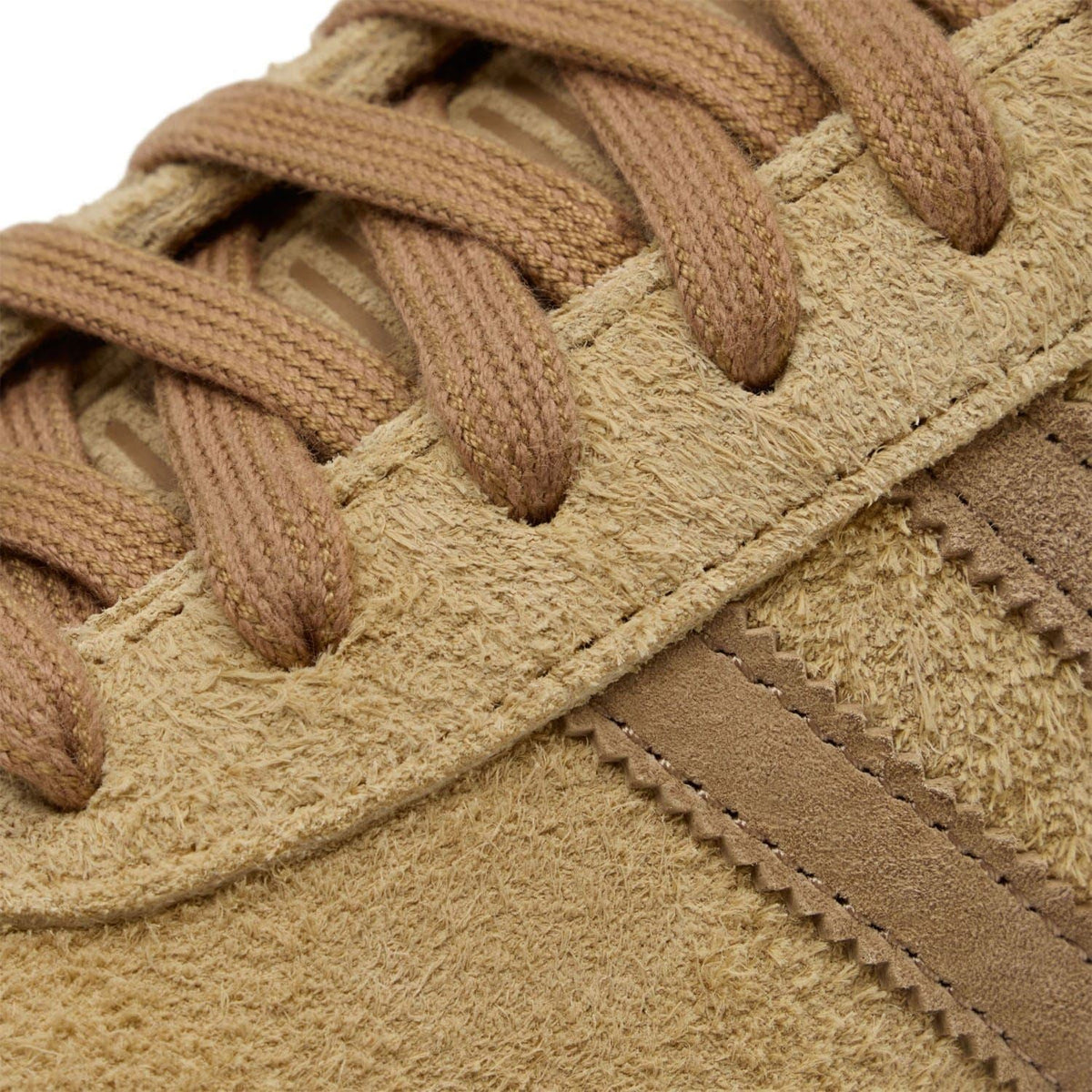 Brown suede trainer close-up with textured laces and contrast stitching