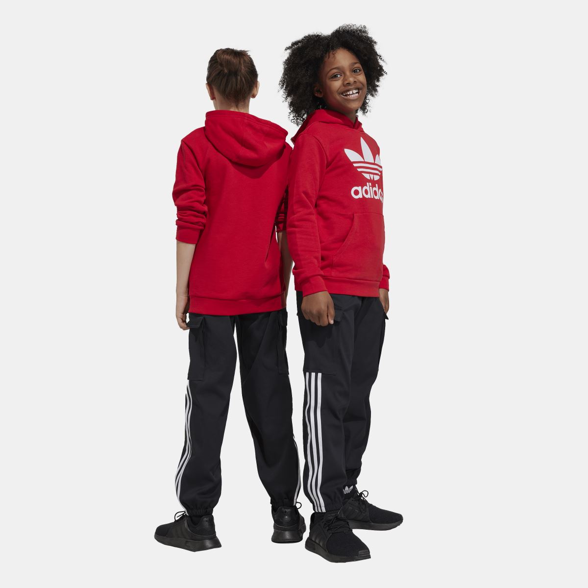 Kids black cargo jogger trousers with white triple stripe side panels and cargo pockets