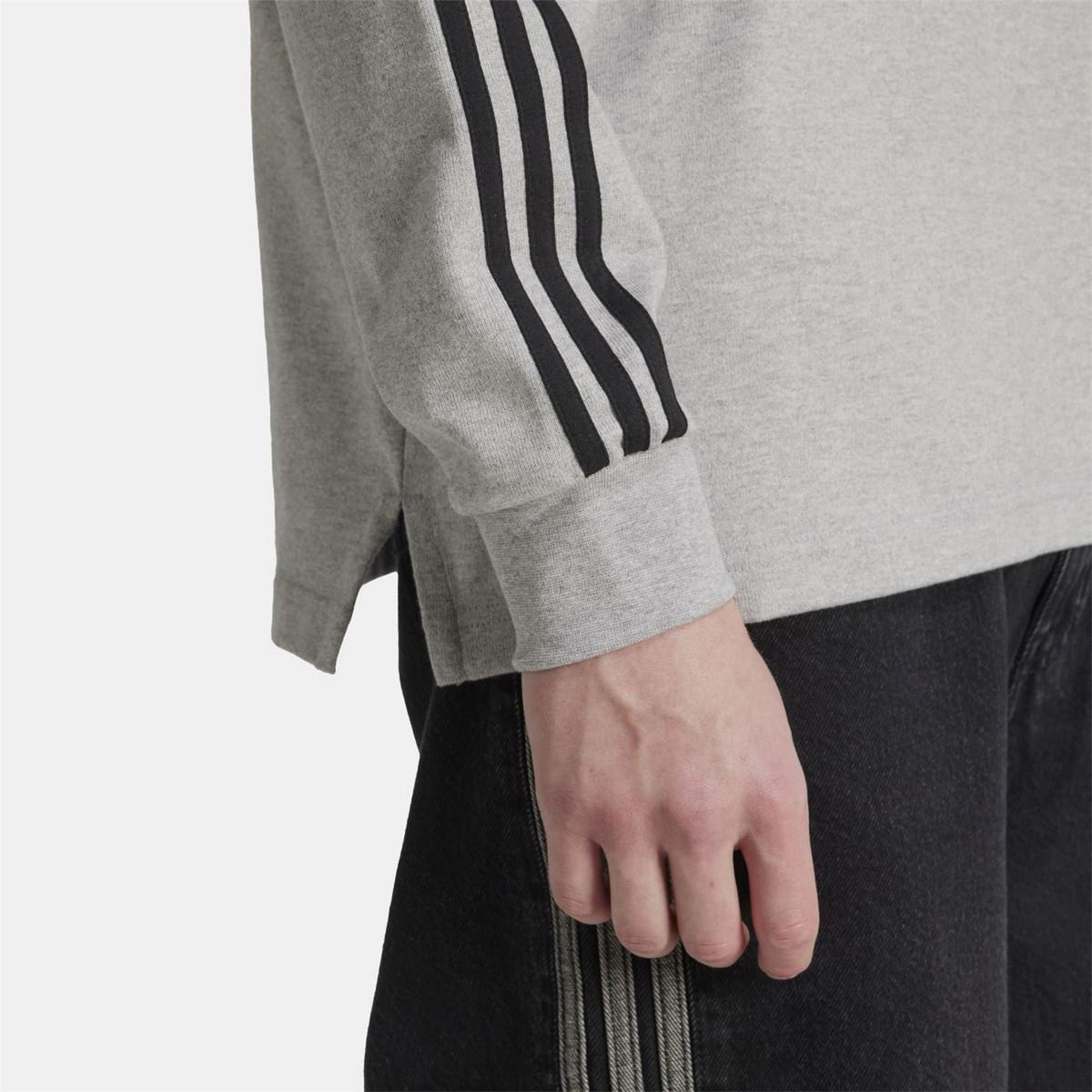 Grey polo sleeve with black three-stripe panel and ribbed cuff; close-up.