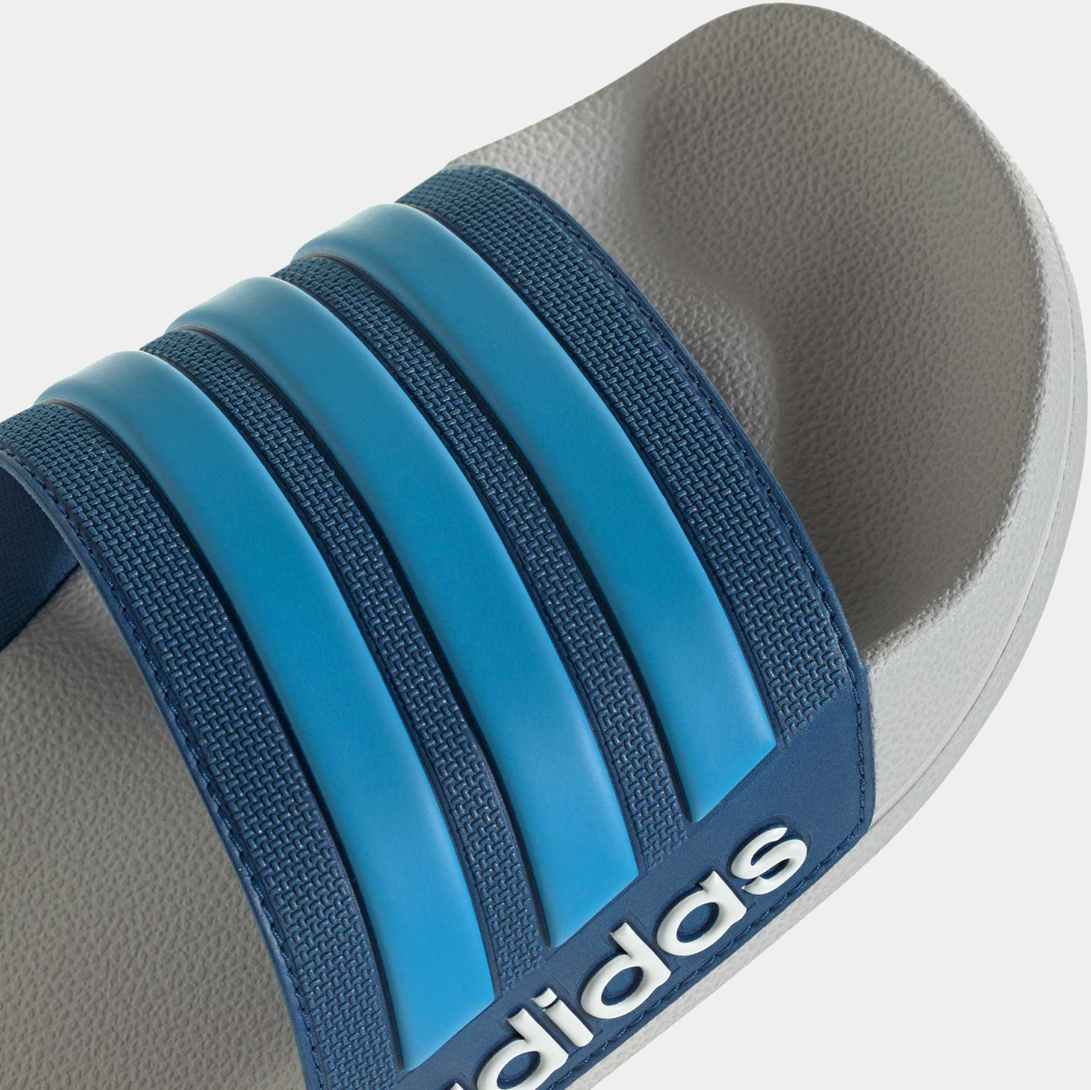 Adilette shower slides close-up of blue three-strap band and textured footbed edge