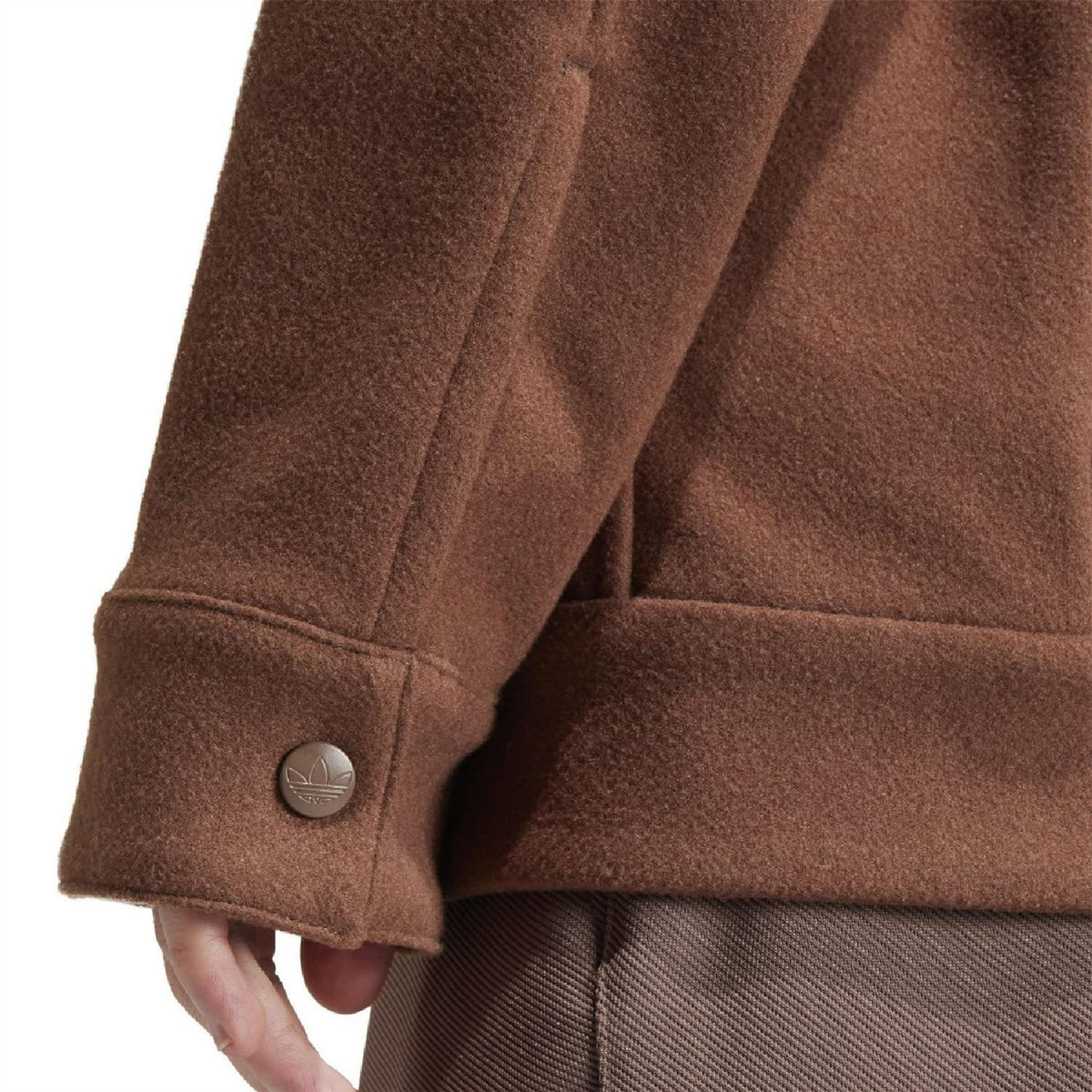 Brown overshirt sleeve cuff with metal button and stitched seam detail