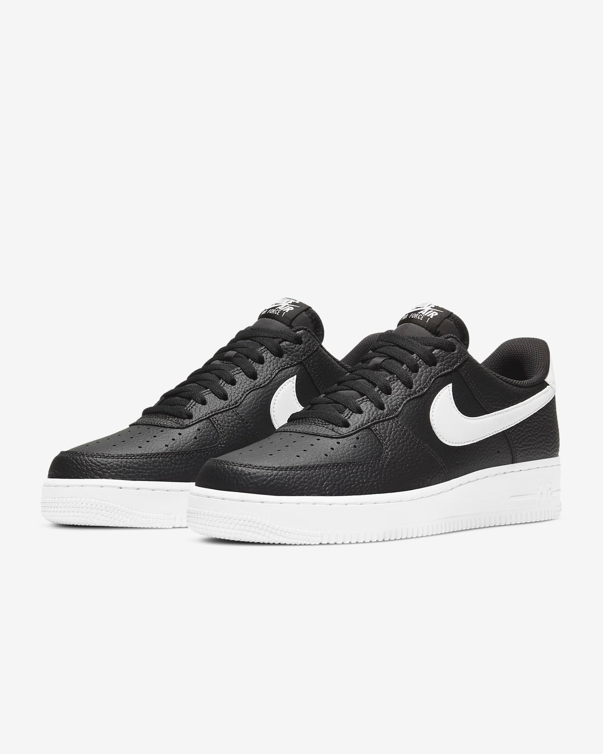 Pair of black low-top sneakers with white Nike swooshes and white midsoles