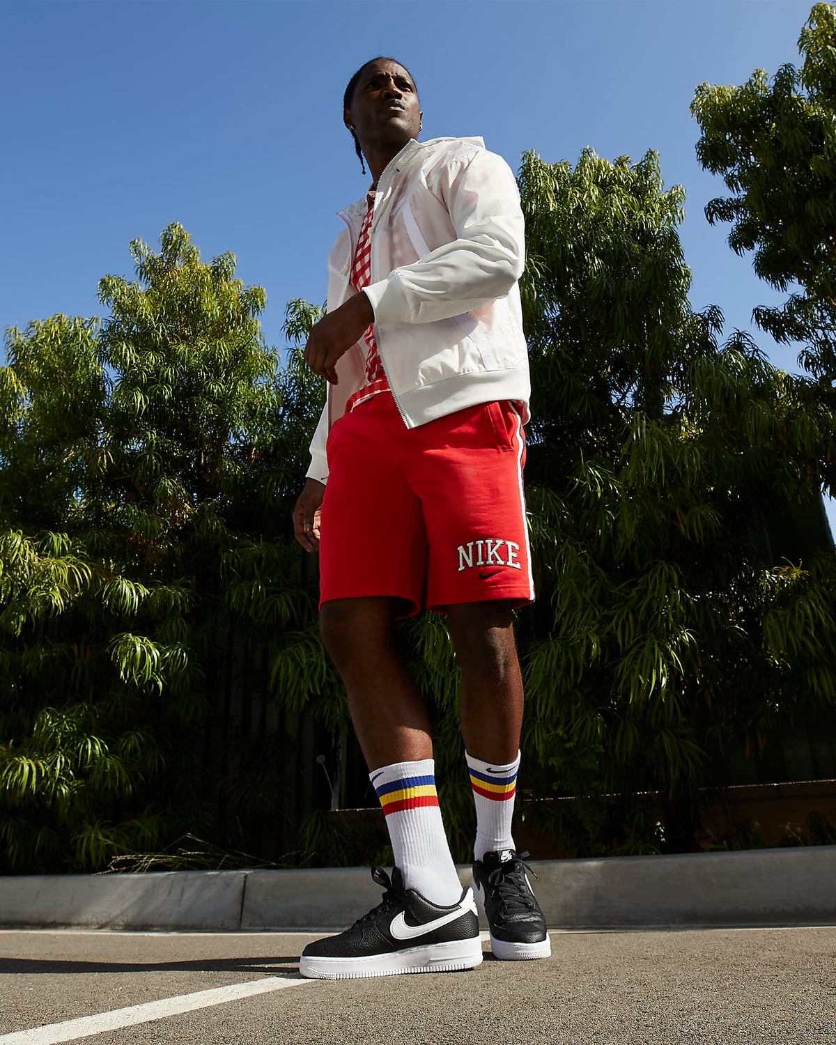Black low-top Nike sneakers with white swoosh and white socks, red shorts visible