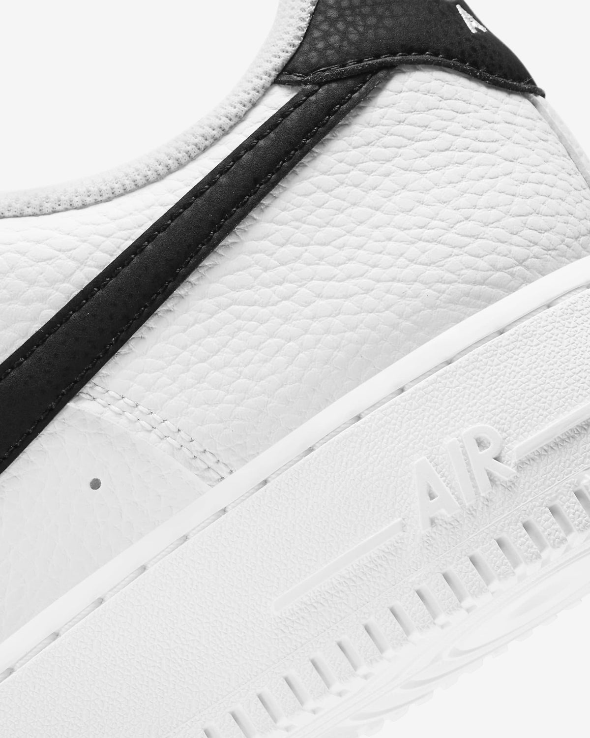 Close-up of white textured upper with black side panel and stitched detail