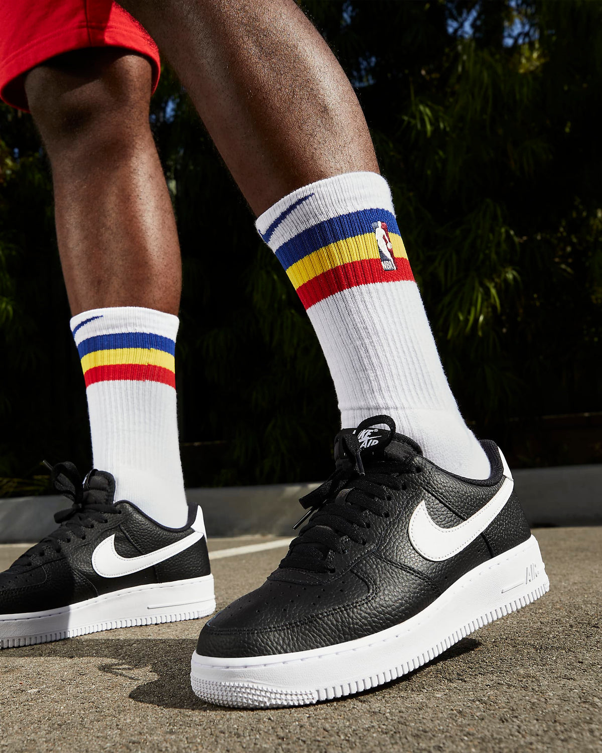 Black low-top sneakers with white Nike swoosh worn on feet outdoors