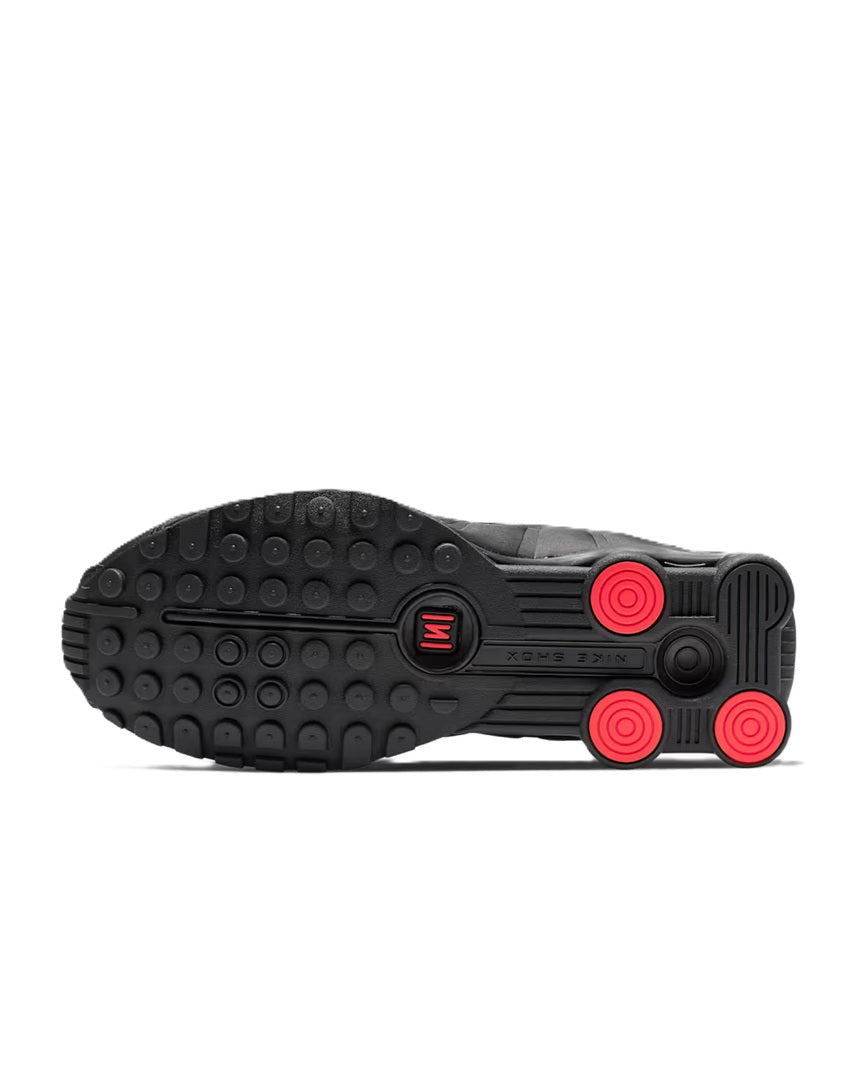 Women's black sneaker outsole with red traction pods and circular hubs