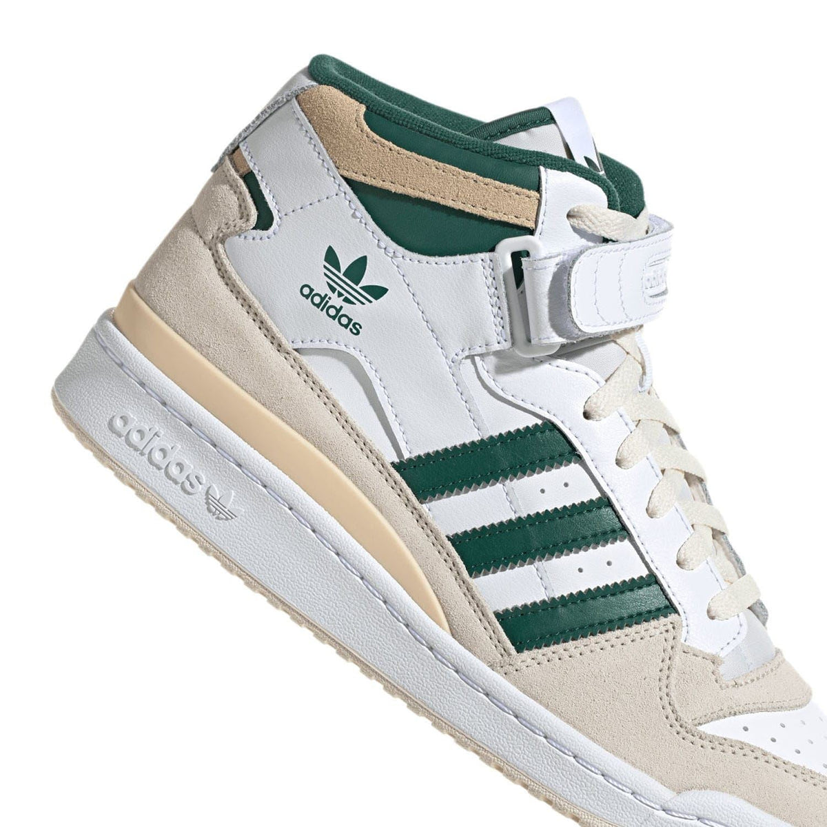 White adidas mid-top sneakers with green stripes, buckle strap, and beige accents