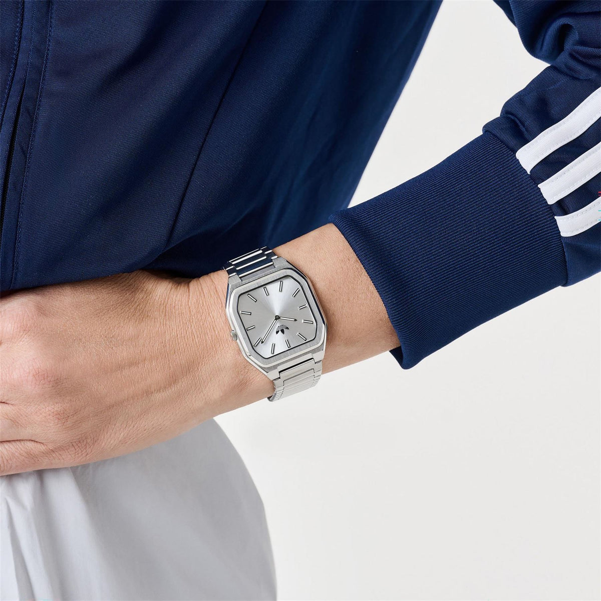 Silver analog wristwatch with rectangular case and metal link bracelet on wrist