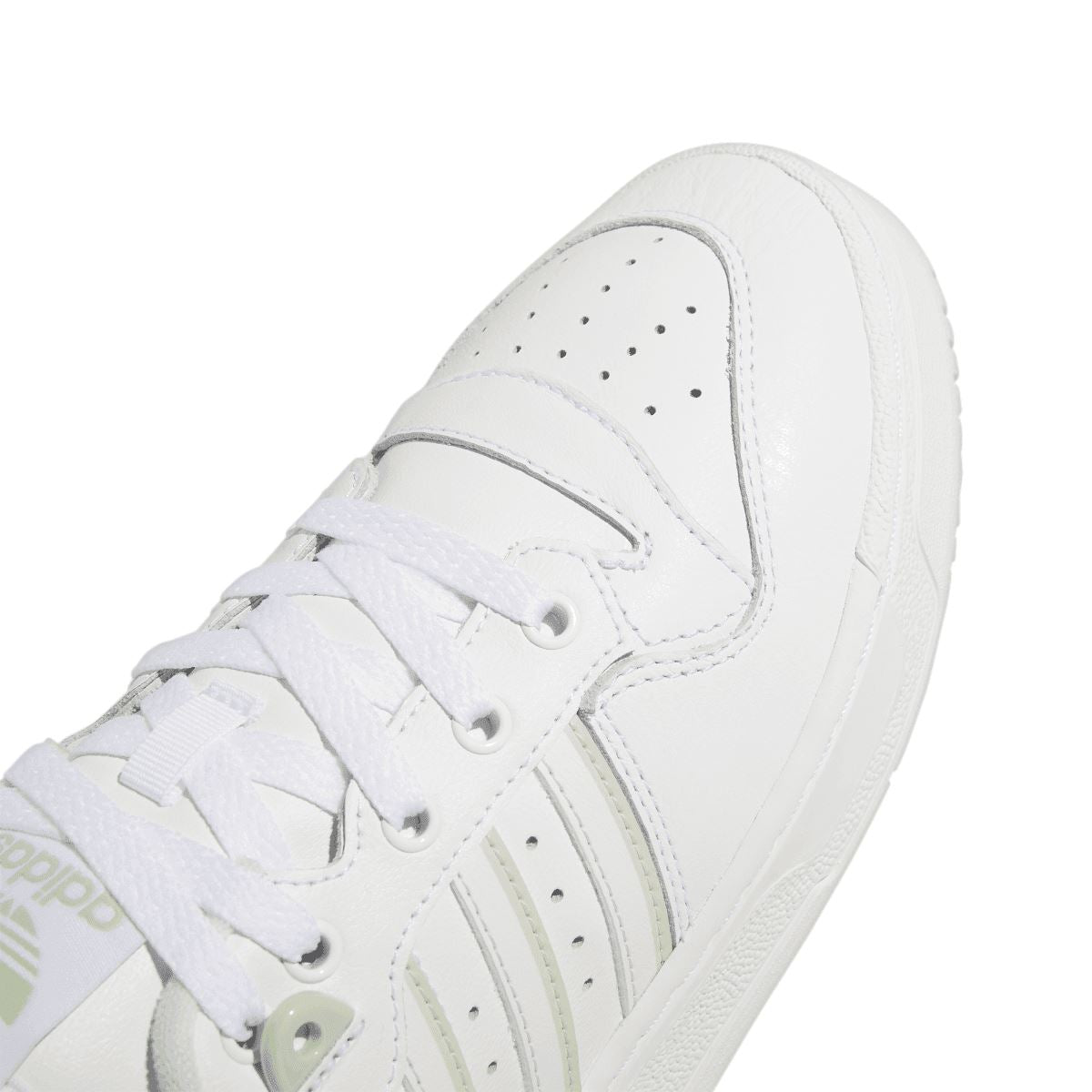 Close-up of white low-top trainer upper with laces, stitching, and three-stripe detail