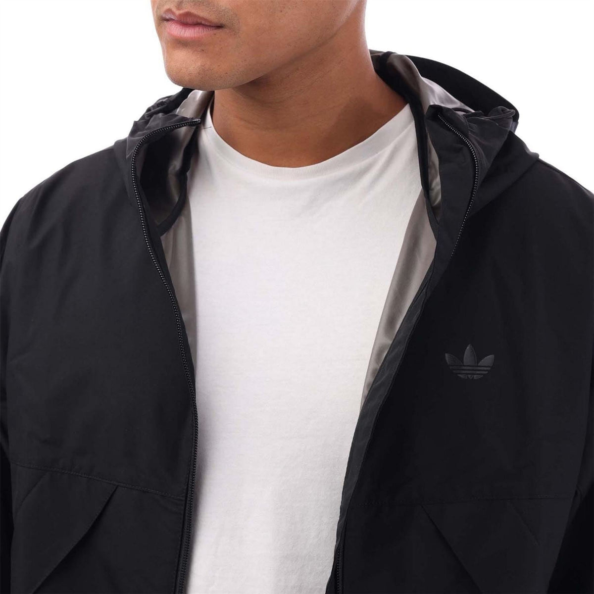 Black hooded shell jacket close-up with front zipper and adidas trefoil logo.