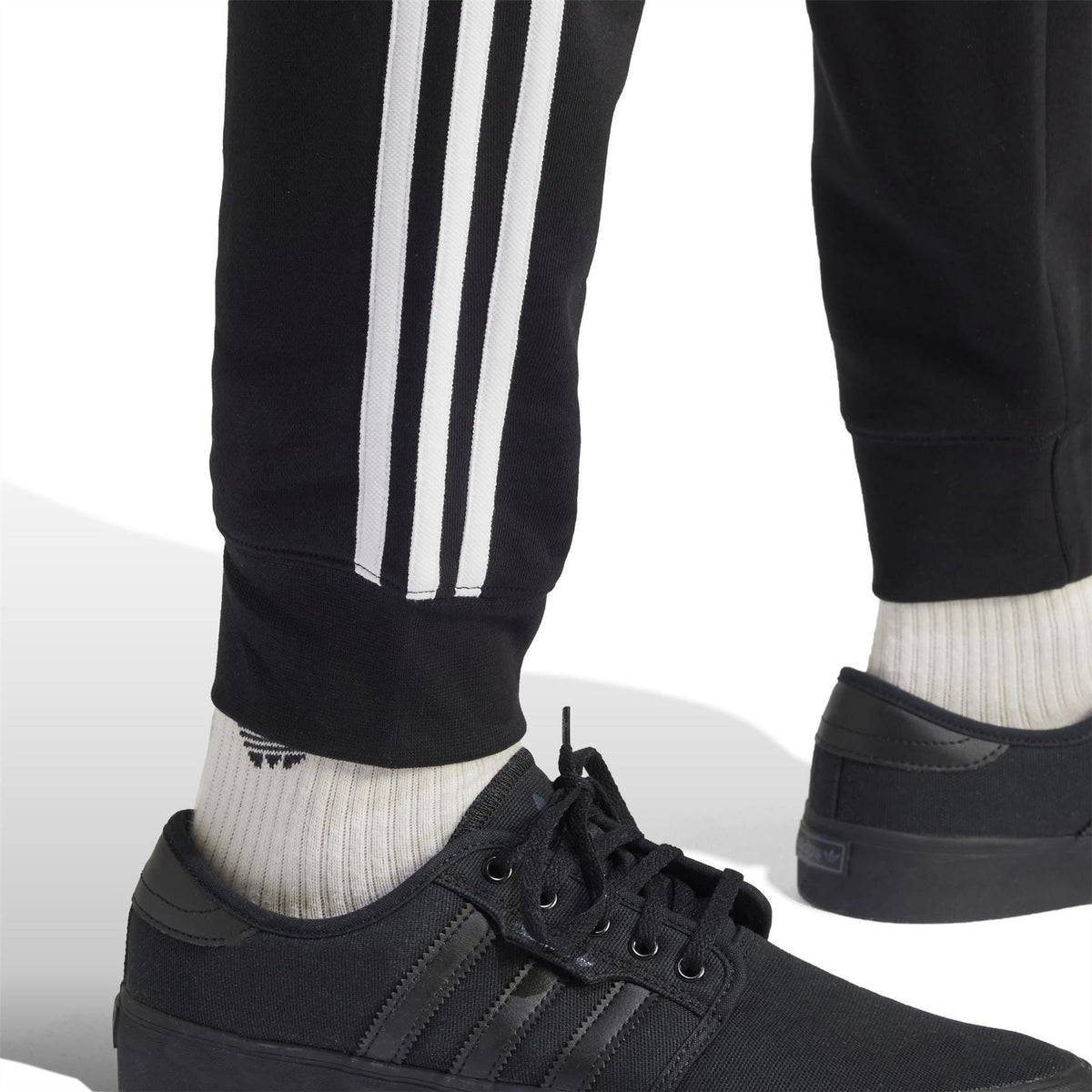 Black slim joggers with white side stripes and ribbed cuffs, with sneakers