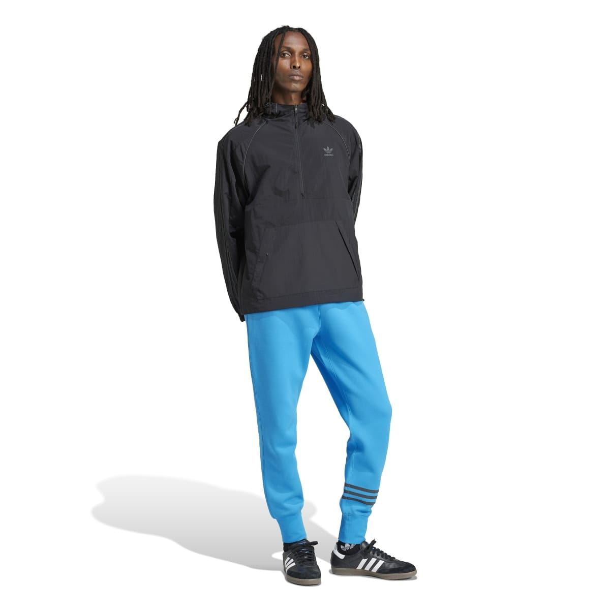 Black adidas anorak jacket with hood and front zip, paired with bright blue pants