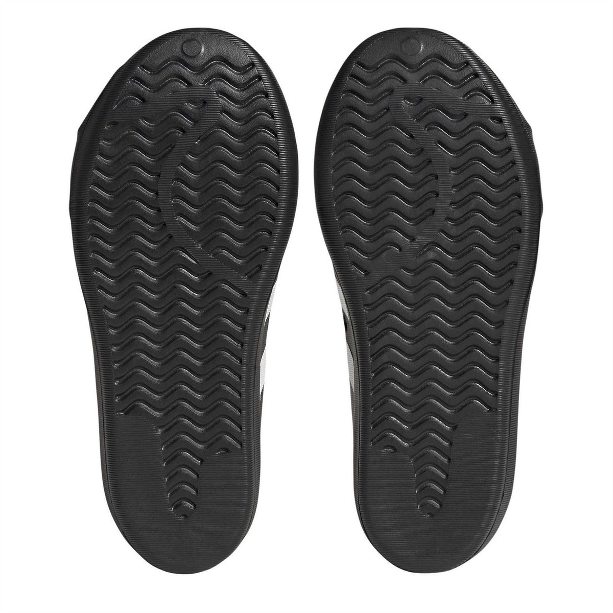 Black sneaker outsoles with wavy tread patterns and adidas logo on each sole