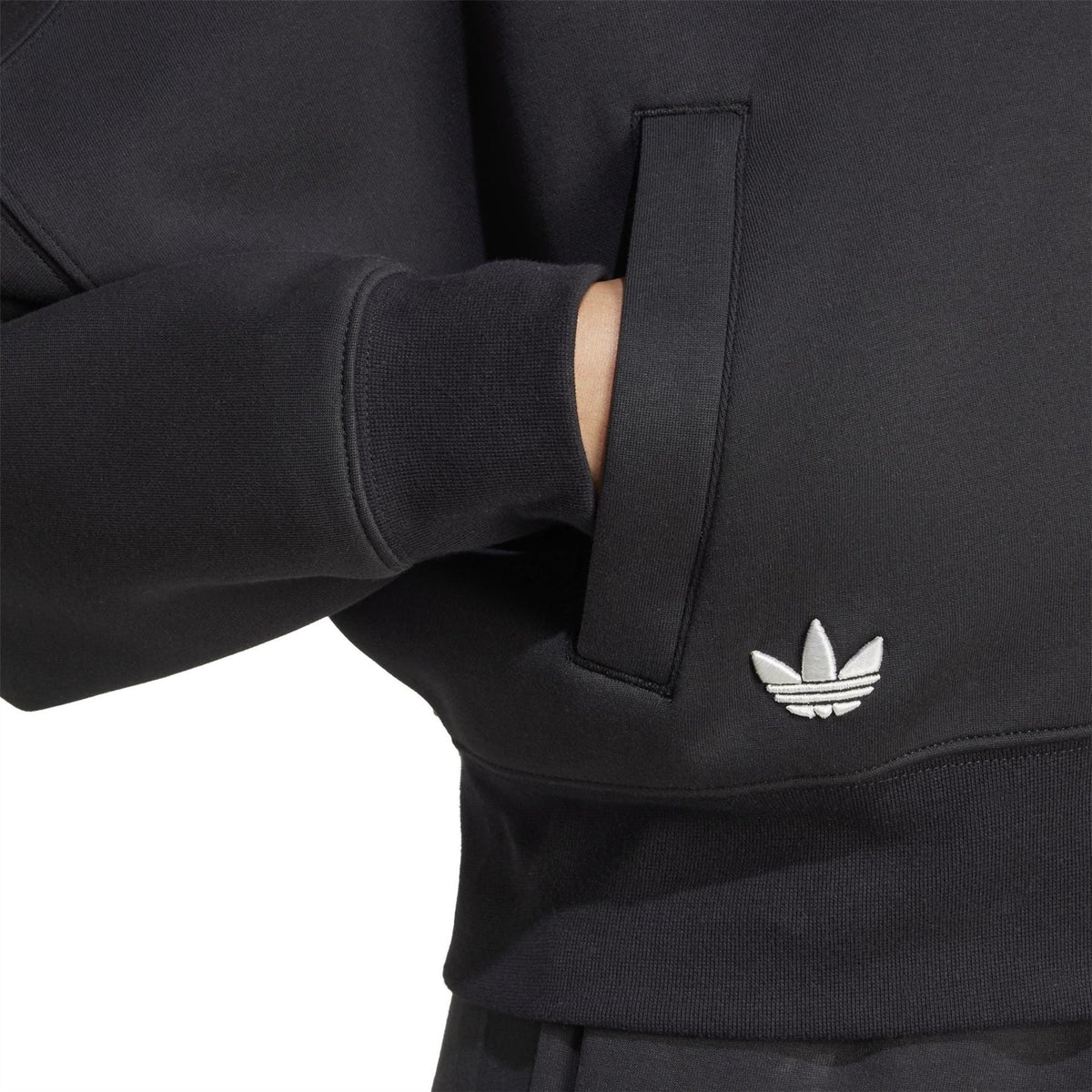 Black track top cuff with adidas trefoil logo and visible zipper placket