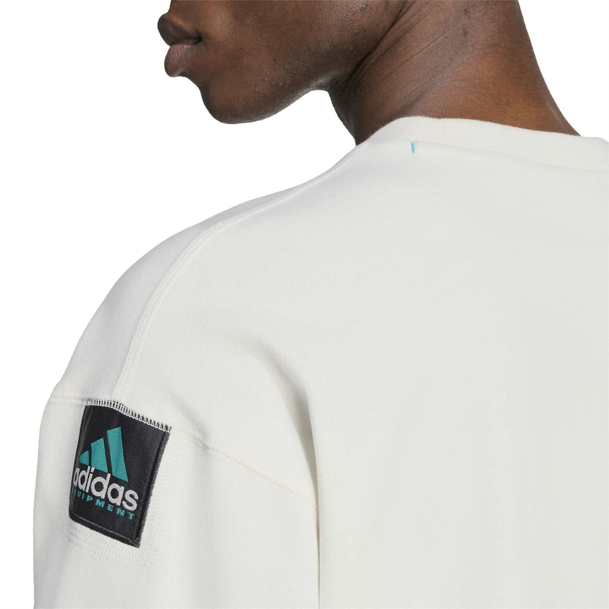Off-white long-sleeve top with adidas Equipment sleeve label patch