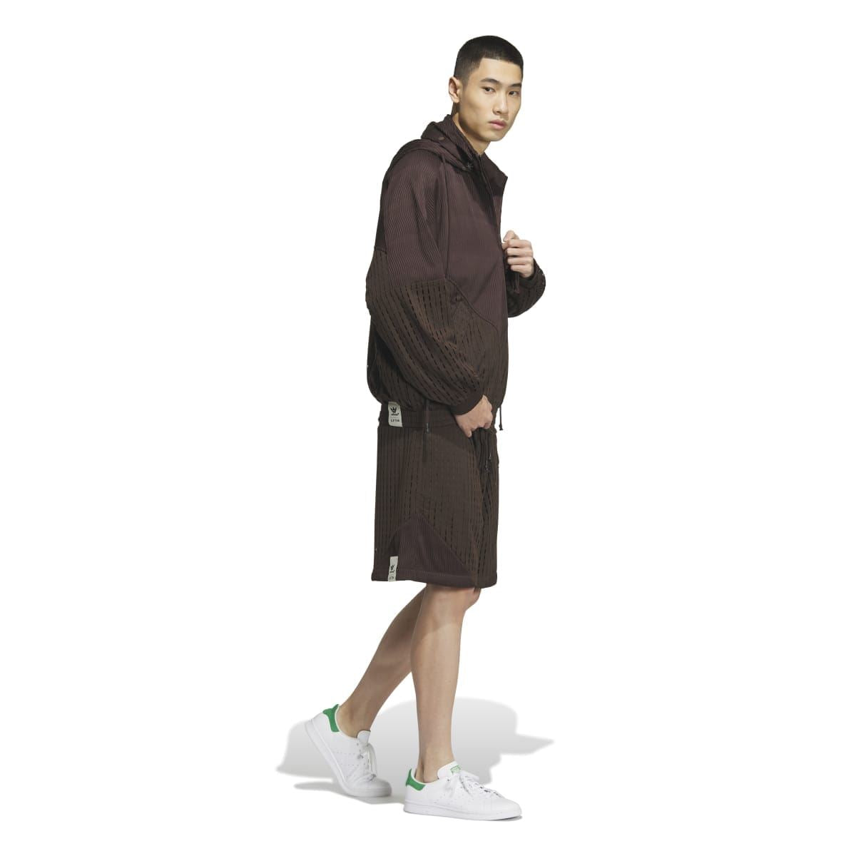 Brown hooded jacket worn on model, side view, with patterned panels and drawcord waistband
