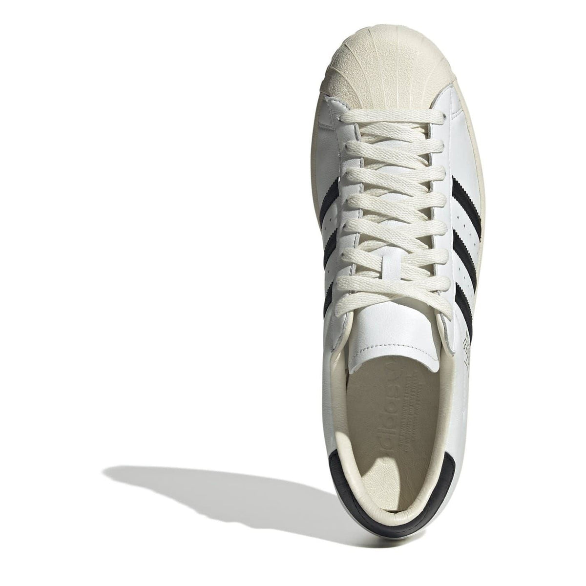 Side view of cream-white lace-up sneakers with black heel lining detail