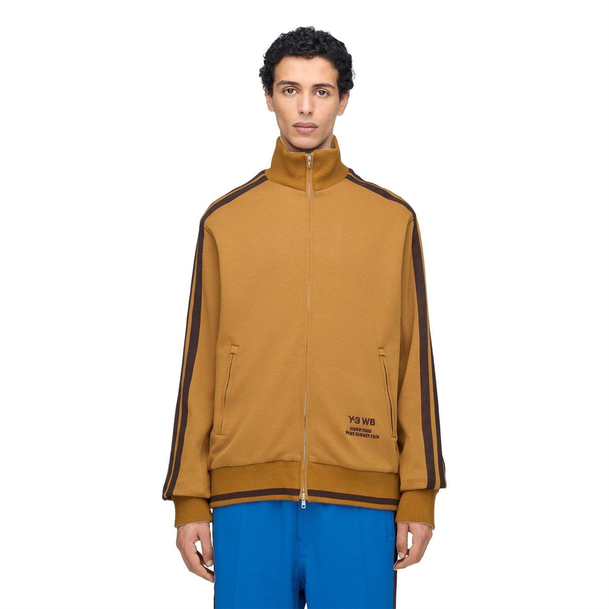 Men's tan Y3 track jacket with full zip, stand collar, side stripes, and logo patch.