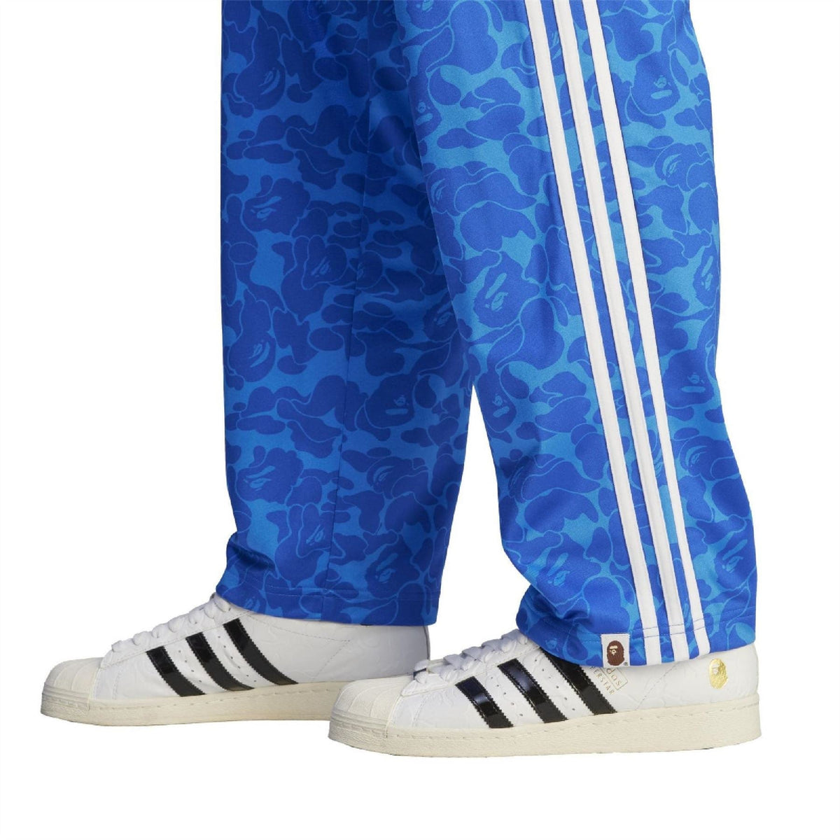 Blue camo track pants with white triple stripes along the sides and tapered cuffs