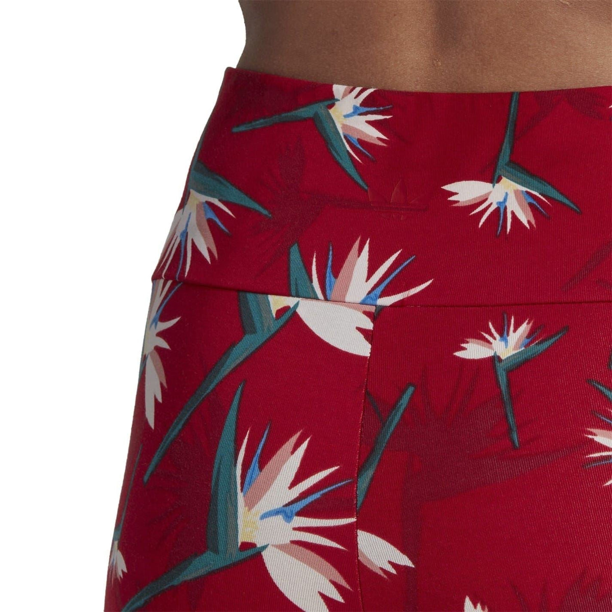 Red tropical-print leggings with floral and leaf shapes, textured fabric close-up