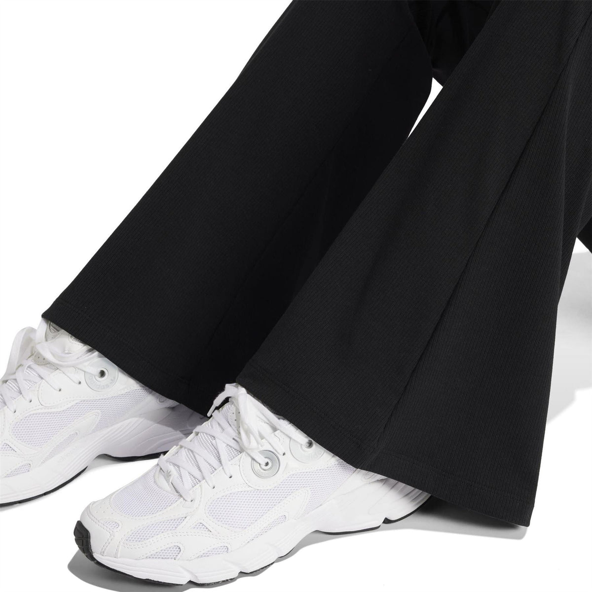 Black flared leggings hem with smooth knit texture and sneakers