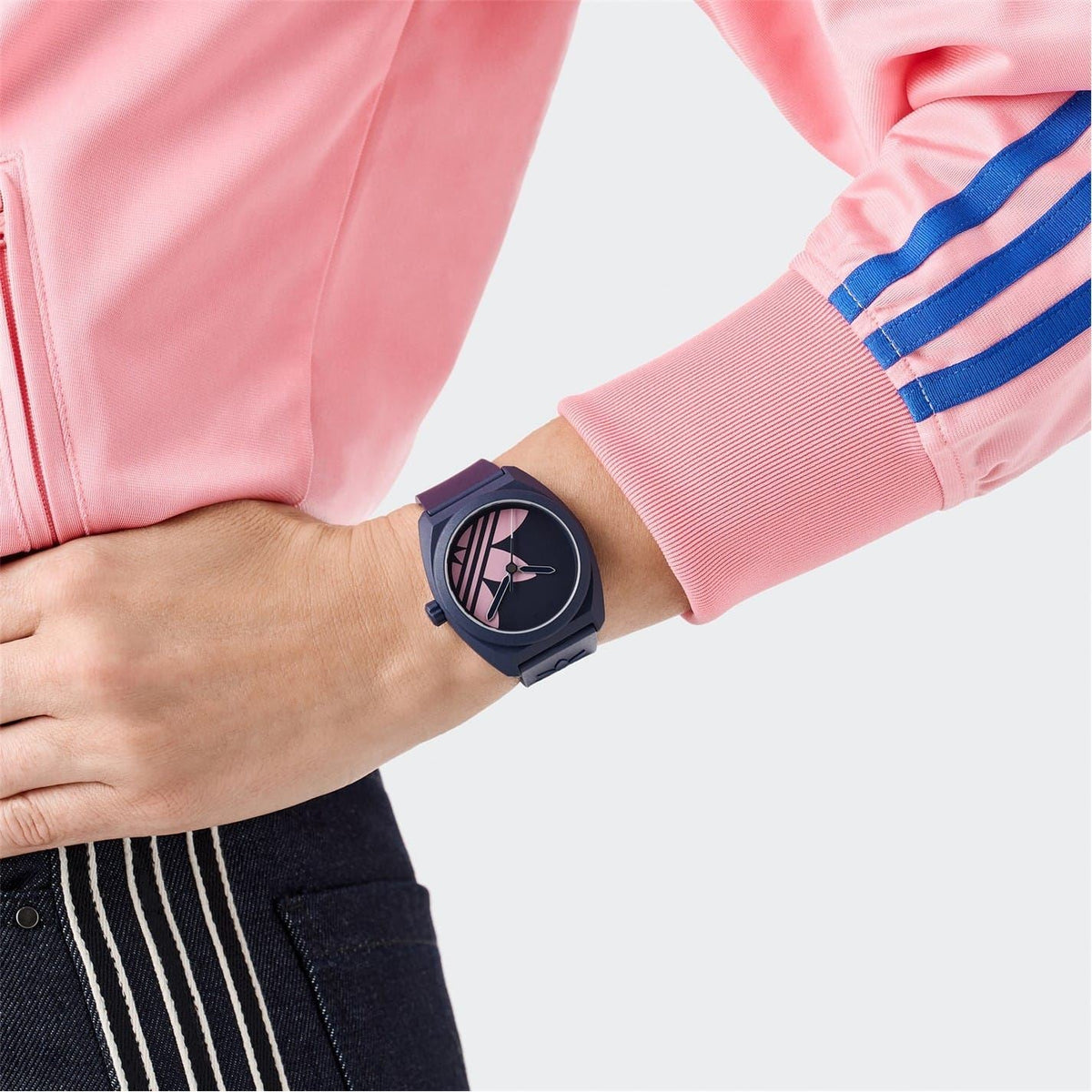 Blue rubber strap analogue watch on wrist, round dark dial with pink graphic