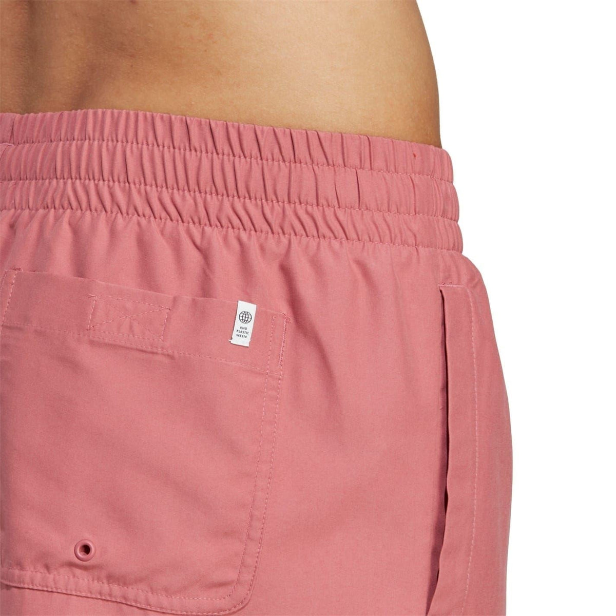 Pink swim shorts close-up with elastic waistband, back pocket, and size label