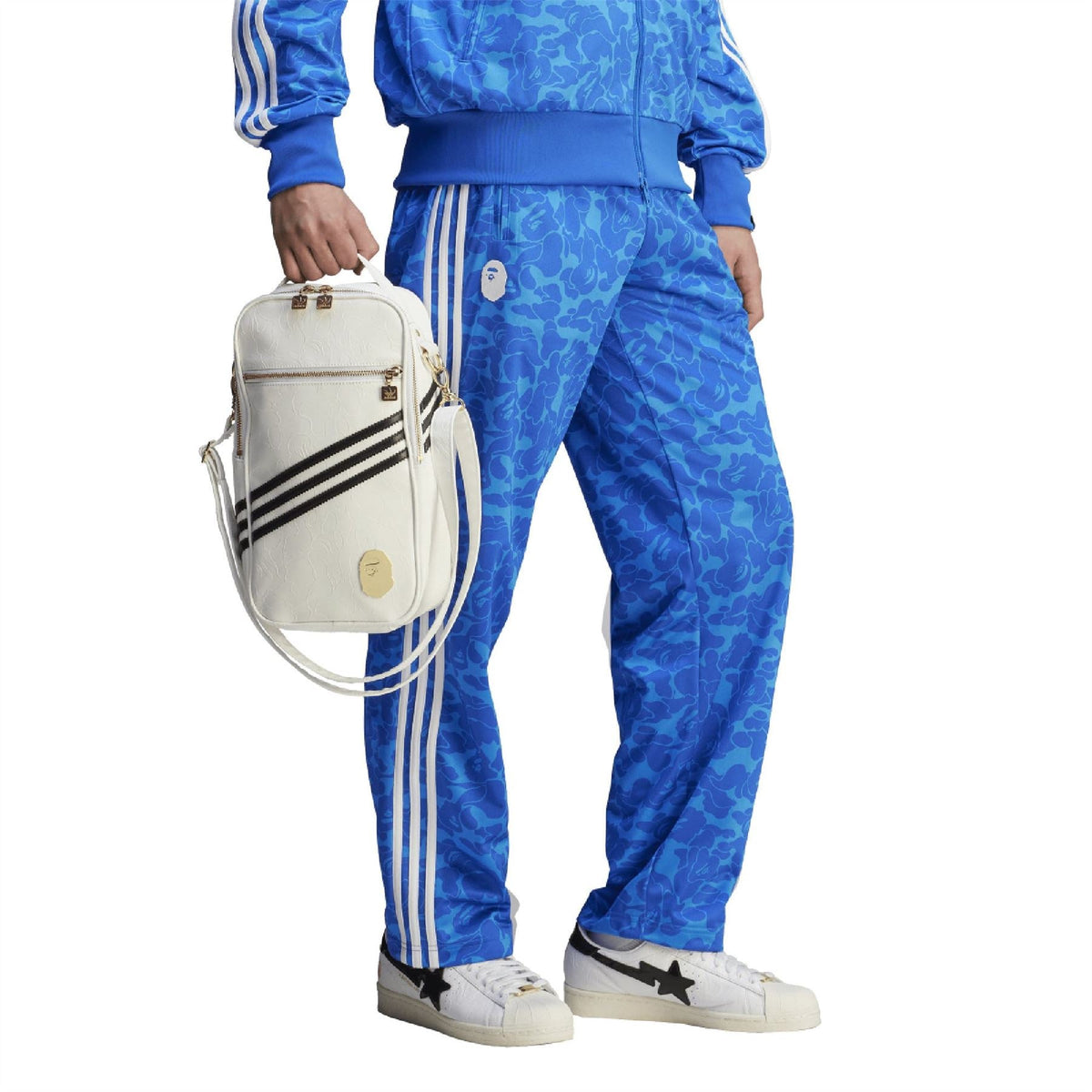 Blue camouflage track pants with white triple side stripes, paired with adidas sneakers