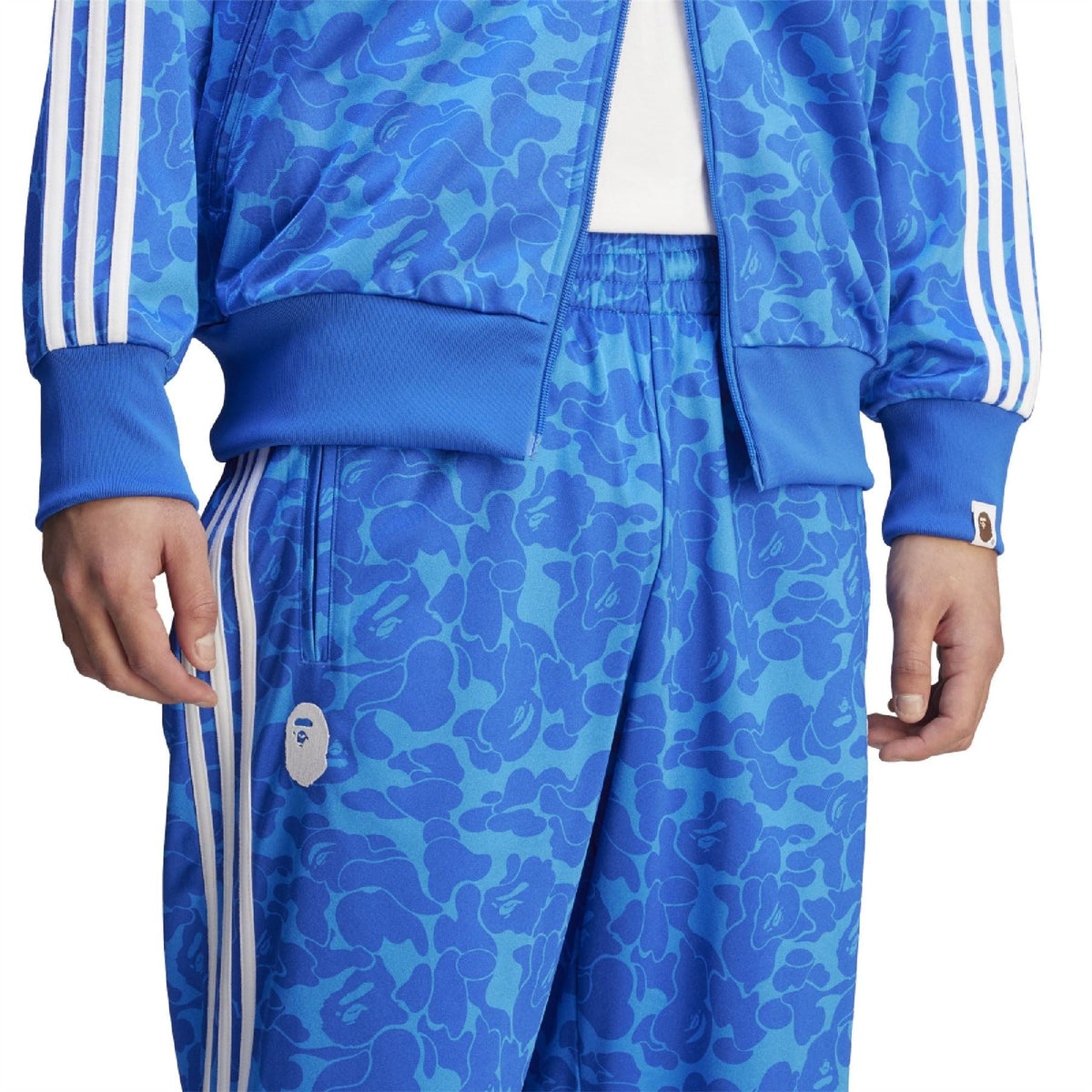 Blue camouflage track pants detail: elastic waistband, side stripe, small logo patch