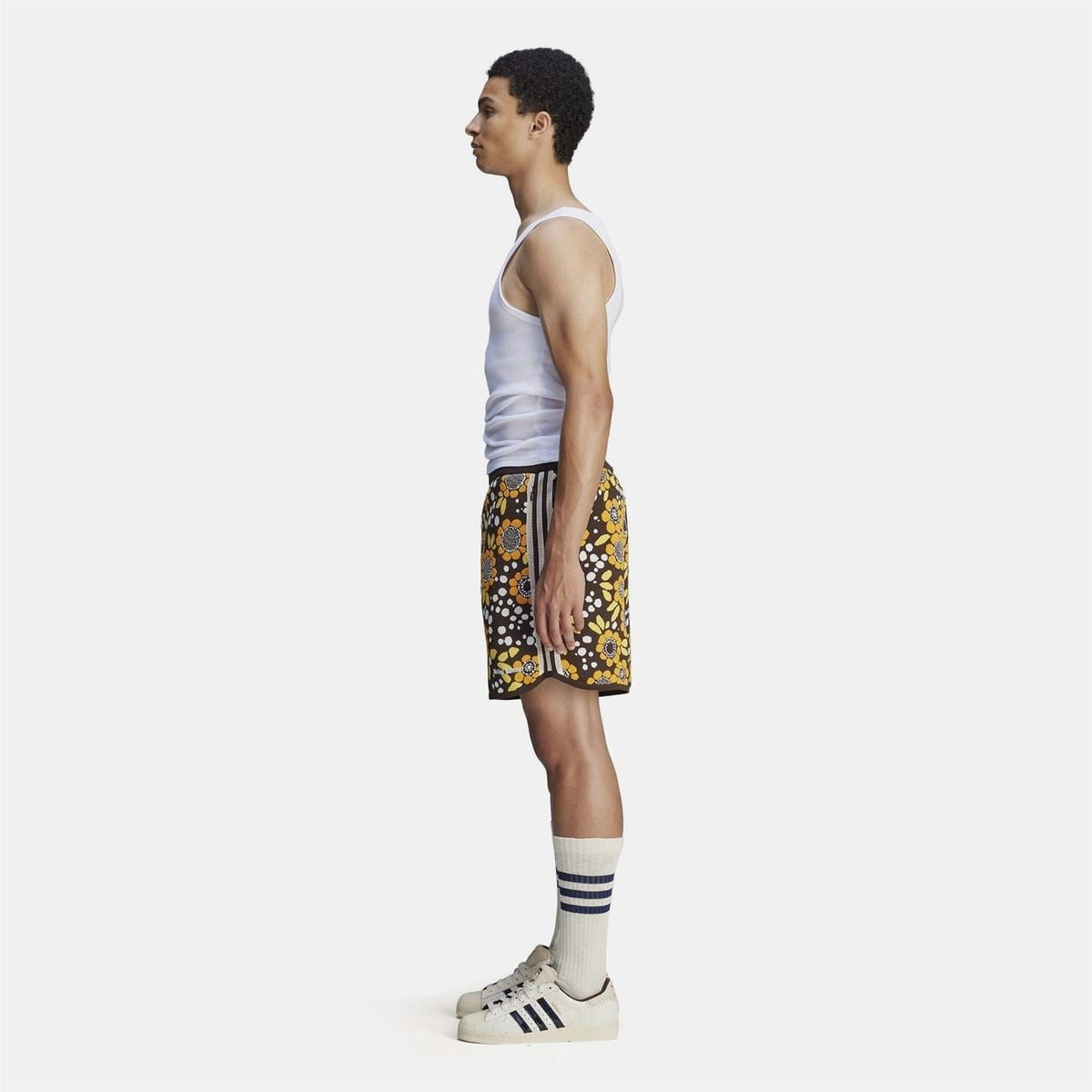 Side view of floral knit shorts, black with yellow orange flower pattern and side stripe