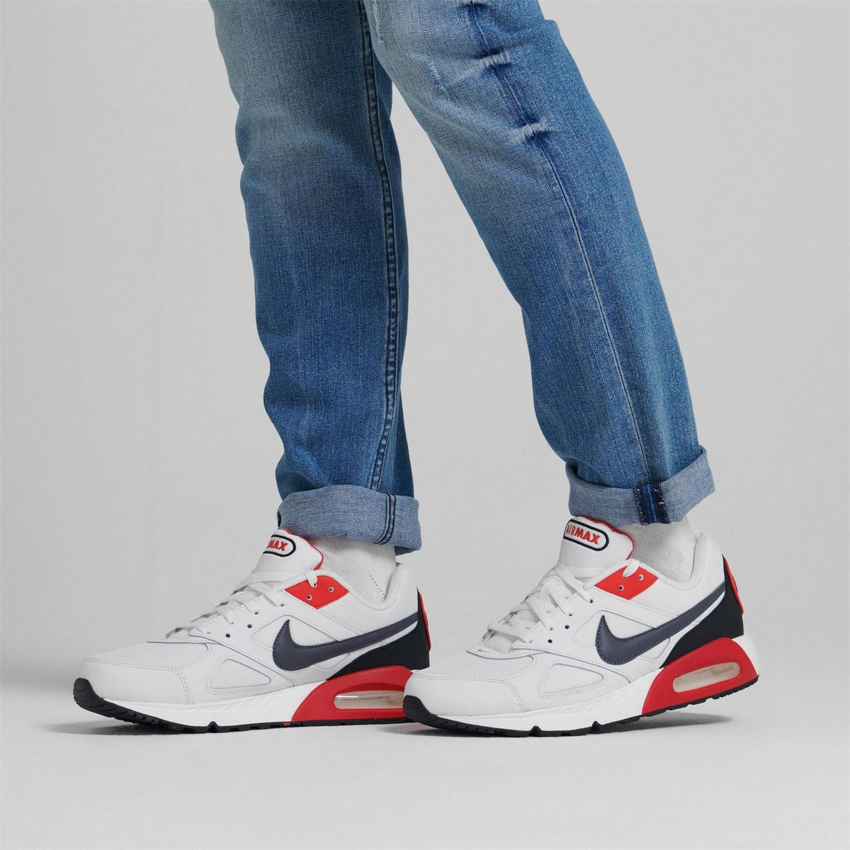 Air Max Ivo trainers worn with blue jeans: white shoes with red and black accents.