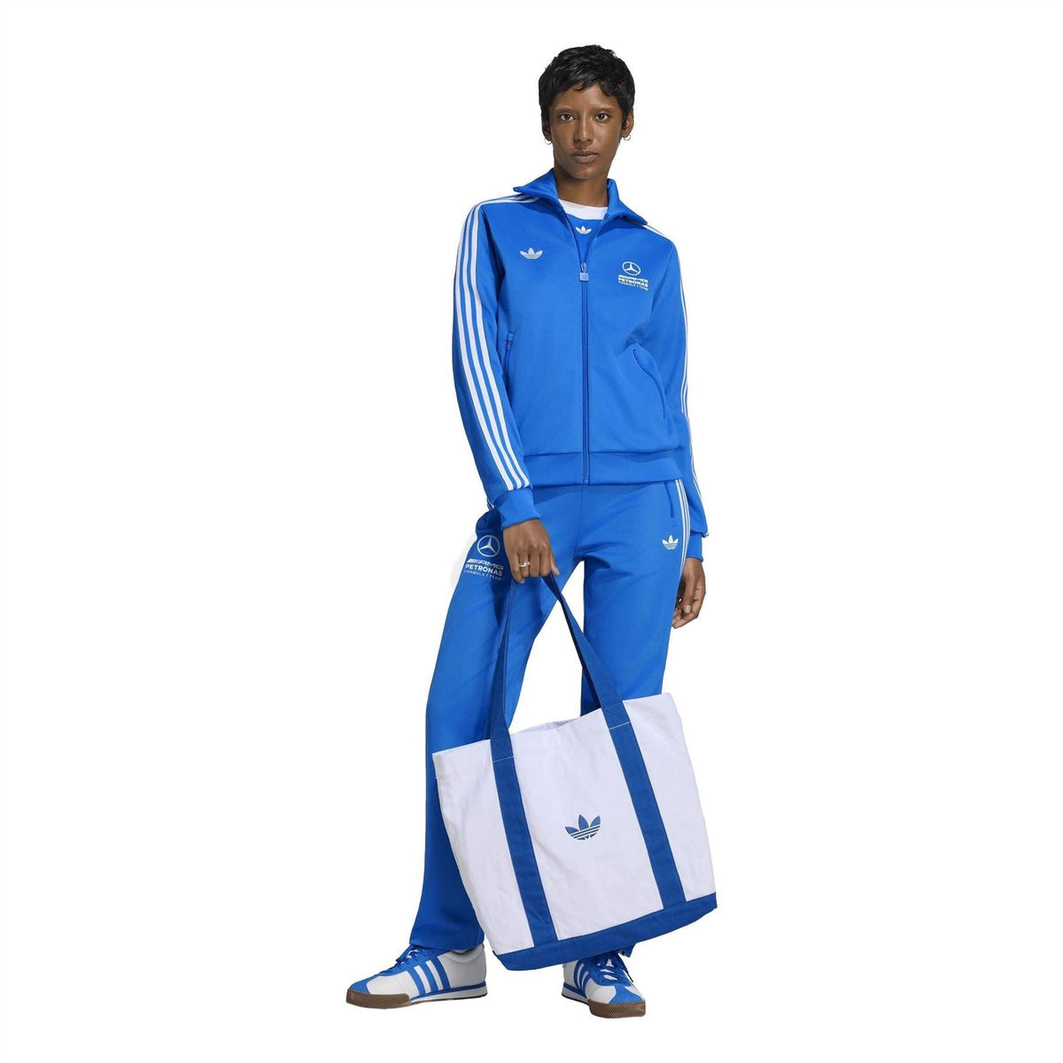 Blue adidas track pants with white side stripes and logo prints on the thigh.