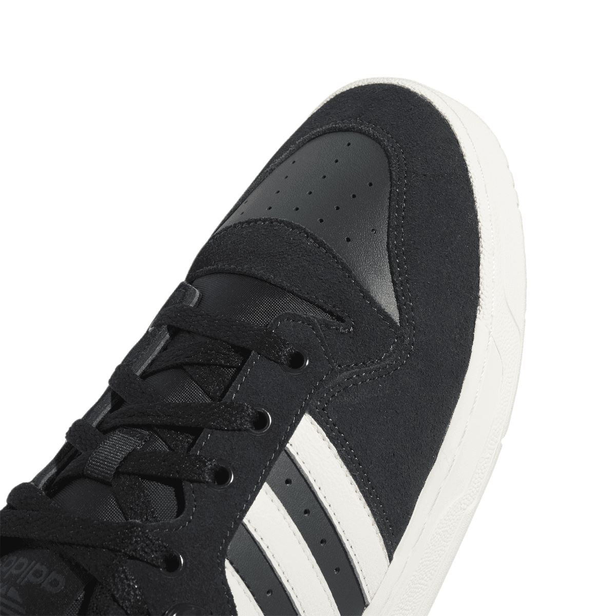 Close-up of black low-top trainer toe with lace-up eyelets and white three stripes