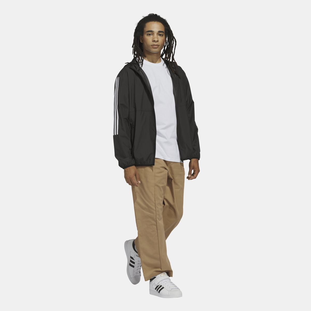 Black adidas Originals hooded windbreaker jacket with white three-stripe sleeves, worn with pants