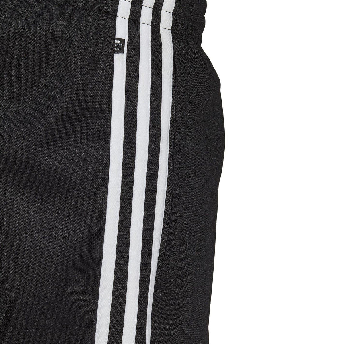 Close-up of black joggers fabric with vertical white three-stripe panel