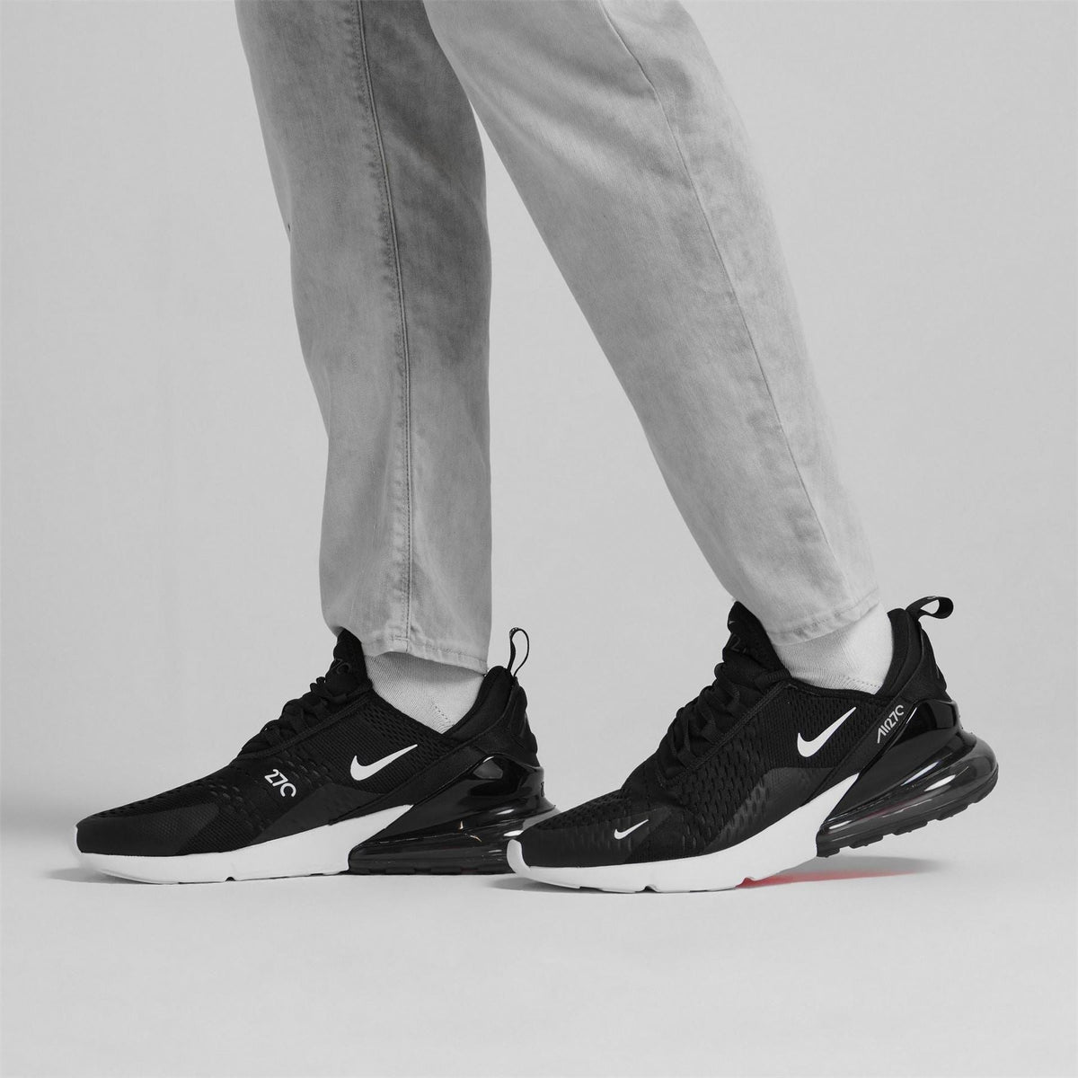 Nike Air Max 270 trainer on feet, black with white and red air details