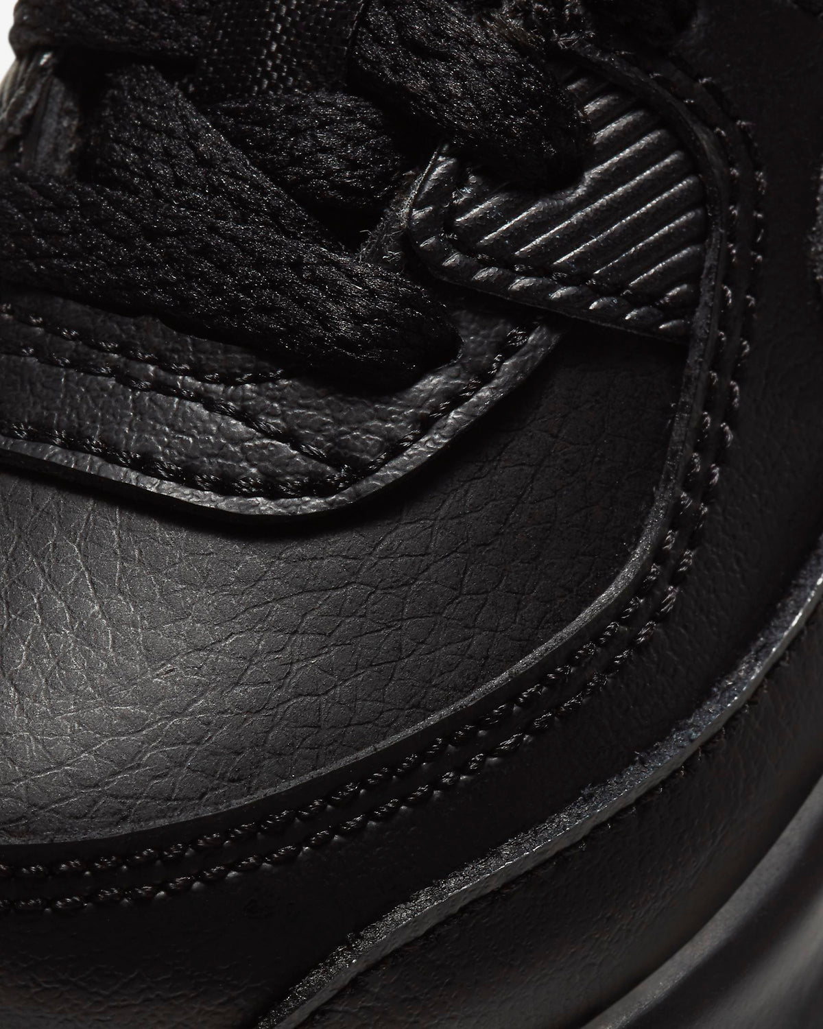 Black leather-look sneaker upper close-up with stitching and lace panel