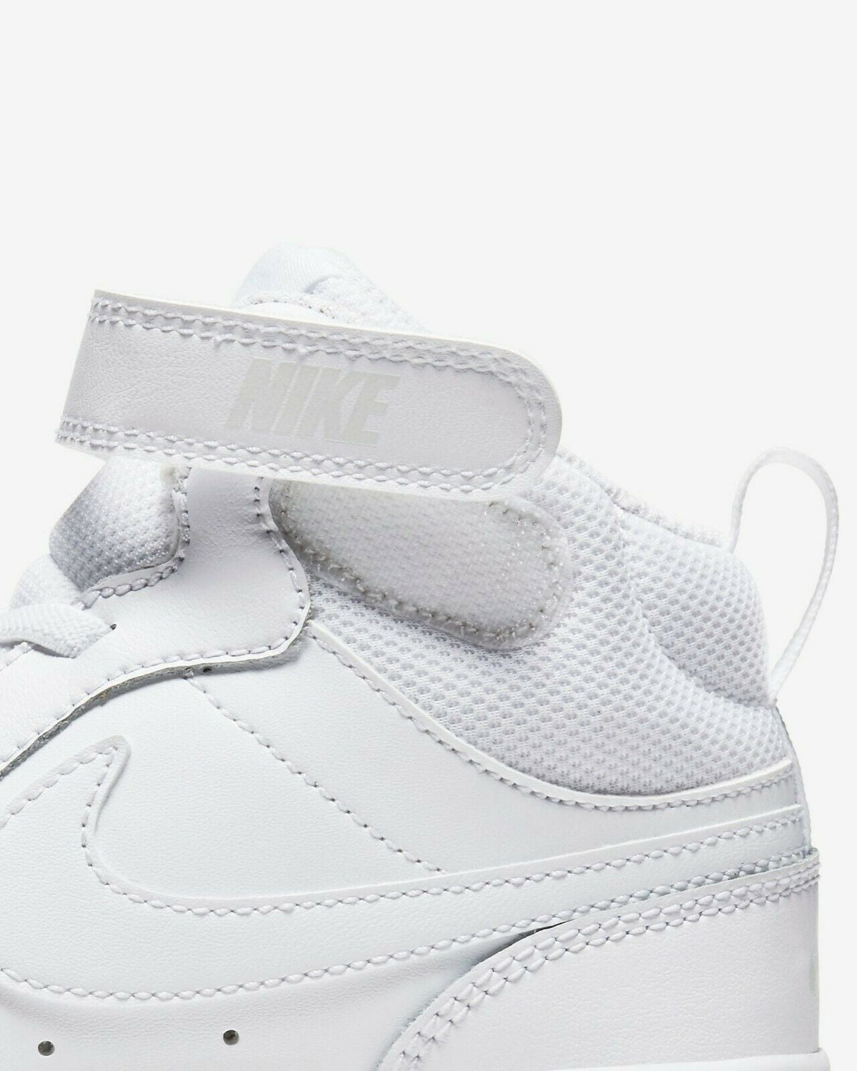 White Nike kids' sneaker upper close-up with stitched panels and mesh lining